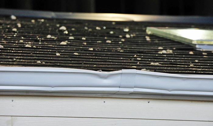 damaged white gutter , shingles , roof , hail damage , storm damaged roof